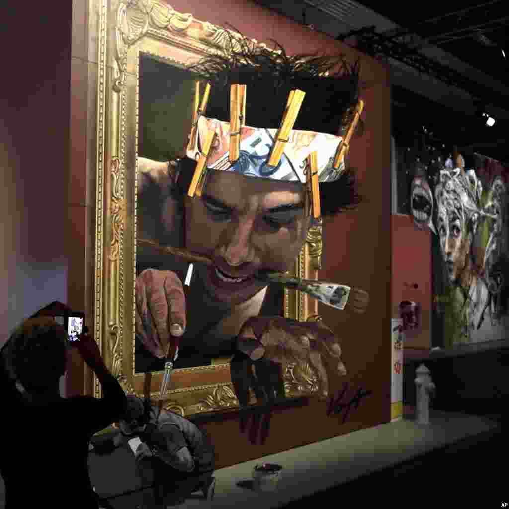 A woman takes pictures of a work by Mexican artist Juandres Vera at the Magic City &#39;The Art of the Street exhibition&#39; in Munich, Germany.