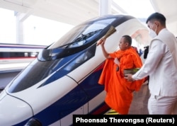 Seorang biksu memberkati kereta api sebelum upacara serah terima proyek kereta api berkecepatan tinggi yang menghubungkan Kota Kunming dengan Vientiane di barat daya China, di Vientiane, Laos, 2 Desember 2021. (Foto: REUTERS)