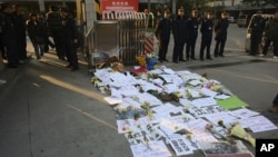 Security guards stand near protest banners and flowers laid outside the headquarters of 'Southern Weekly' newspaper in Guangzhou, Guangdong province, China, January 7, 2013. 