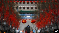 Un guardia de seguridad con mascarilla camina por la calle Quanmen, normalmente popular entre los turistas pero que aparece casi vacía, en Beijing, el domingo 16 de febrero de 2020. (AP Foto/Andy Wong)