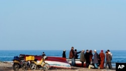 Tunisian people stand at the seaside in coastal town Zarzis in southeastern Tunisia, February 18, 2011
