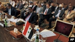 The Syrian flag and a sign in Arabic that reads, "the Syrian Arabic Republic," is seen in front of the empty chair of the Syrian representative during the Arab League Syria Group and foreign ministers meeting in Cairo, Egypt Sunday, February 12, 2012.