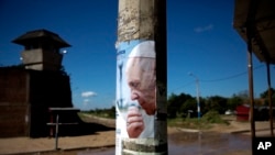 FILE - A poster of Pope Francis covers a lamppost outside Palmasola prison where the pontiff visited inmates in Santa Cruz, Bolivia, July 10, 2015.