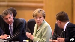 German Chancellor Angela Merkel (C) chats with her delegates as she attends a bilateral meeting with Chinese Premier Li Keqiang at the Great Hall of the People in Beijing, China, July 7, 2014.