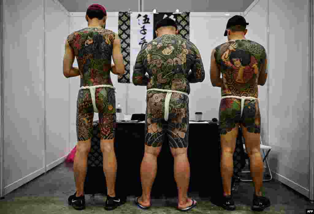 Three men display their tattoos during the International Malaysia Tattoo Expo in Kuala Lumpur.