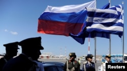 FILE - Greek police and army officers stand by Greek, Russian and EU flags as they wait for the arrival of Russian President Vladimir Putin in Athens airport, May 27, 2016. 
