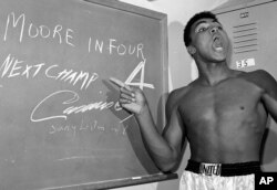 FILE - Young heavyweight boxer Cassius Clay, who later changed his name to Muhammed Ali, points to a sign he wrote on a chalk board in his dressing room before his fight against Archie Moore in Los Angeles, in this Nov. 15, 1962 file photo.