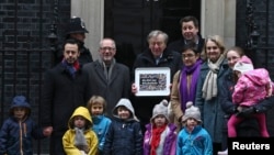 Labour peer Alf Dubs (C) poses with protestors as he delivers a petition to Number 10 Downing Street opposing the closure of a government scheme to bring unaccompanied child refugees to Britain from Europe, in London, Feb. 11, 2017. 