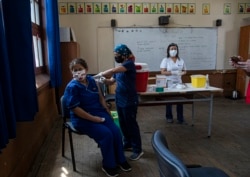 FILE - In this Monday, Feb. 15, 2021, file photo, a teacher receives a shot of the CoronaVac vaccine for COVID-19, by China's Sinovac Biotech, at Salvador Sanfuentes public school during the start of the vaccinations for educators in Santiago, Chile. (AP