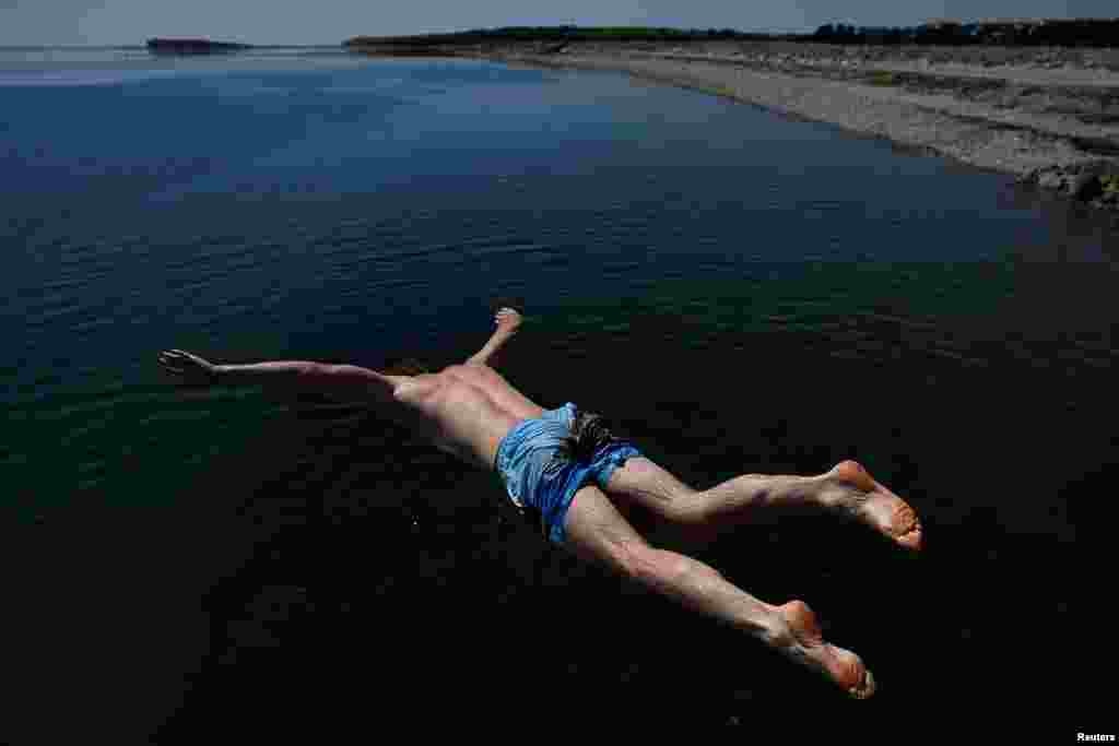 A man dives into the sea at Salthill Beach during sunny weather in Galway, Ireland.