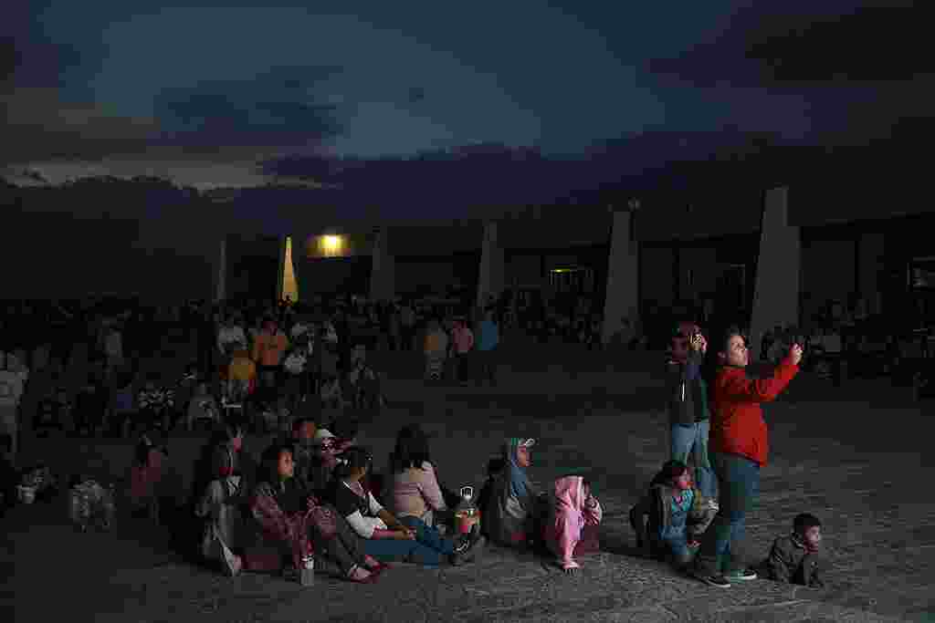 Los peregrinos miran en una pantalla de televisión la cobertura de la visita papal a México, mientras esperan el encendido de la nueva iluminación de la estatua de Cristo Rey, inaugurada en forma remota por el papa Benedicto XVI. (AP)