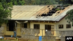 FILE - A woman stands outside the damaged roof of a school's dormitory, after it was set on fire, in Bafut, in the northwest English-speaking region of Cameroon, Nov. 15, 2017. 
