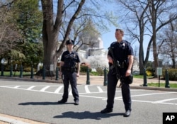 Law enforcement officers keep watch around the north front of the U.S. Capitol in Washington. The building was locked down after a gunshot sounded, April 11, 2015.