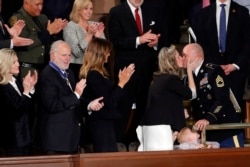 Amy Williams kisses her husband Sgt. 1st Class Townsend Williams after he surprised her by appearing at the State of the Union address by President Donald Trump in a joint session of Congress on Capitol Hill in Washington, Tuesday, Feb. 4, 2020