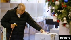 Warga Jepang memasukkan kertas suara dalam pemilihan umum parlemen di Tokyo (14/12). (Reuters/Thomas Peter)