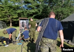 Members of the Canadian Armed Forces install electricity for the tents erected to house asylum-seekers at the Canada-U.S. border in Lacolle, Quebec, Aug. 9, 2017.