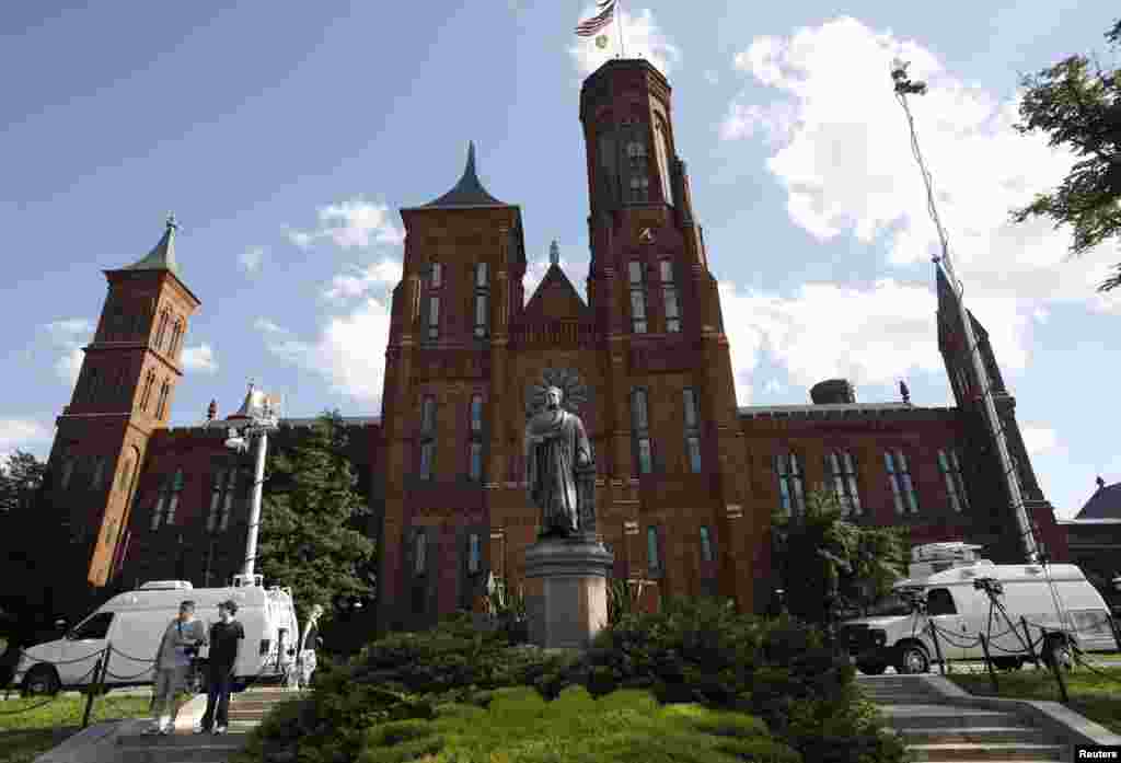 Live news television vans are parked alongside a statue of Joseph Henry, the first secretary of the Smithsonian Institution, after it was vandalized with green paint, outside the institution's Washington headquarters, July 29, 2013. 