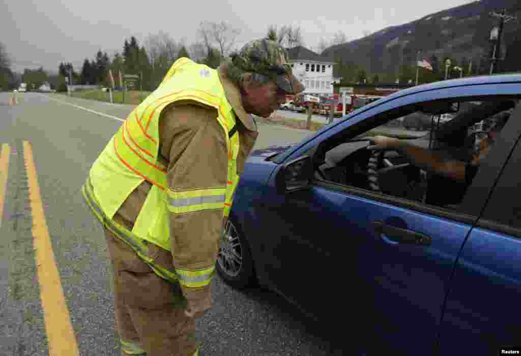 An emergency worker instructs vehicles to turn around after a large mudslide blocked Highway 530 near Oso, Washington, March 22, 2014. 