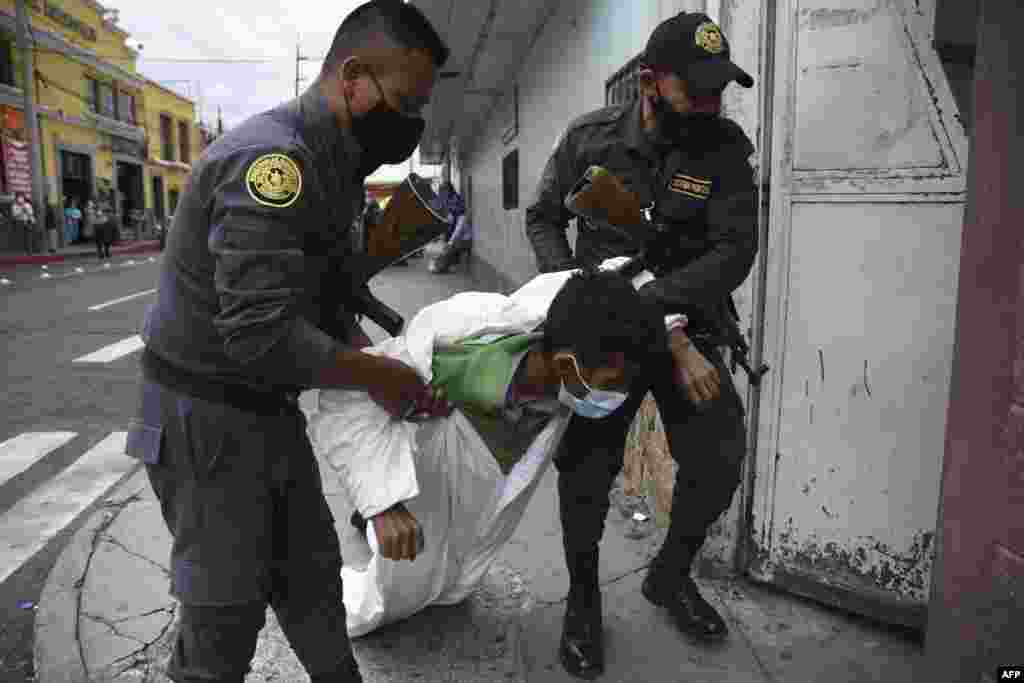 Penitentiary system guards carry an inmate with symptoms related to the novel coronavirus at the COVID-19 unit of San Juan de Dios hospital in Guatemala City, July 13, 2020.