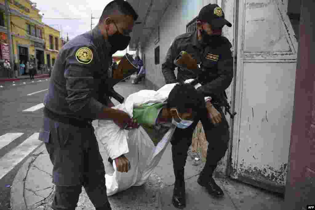 Penitentiary system guards carry a prisoner showing signs related to the new coronavirus, at the COVID-19 unit of San Juan de Dios hospital in Guatemala City, July 13, 2020.