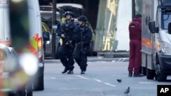Armed British police officers walk within a cordoned off area after an attack at the London Bridge, June 4, 2017, that killed eight people.