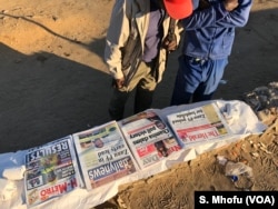 Zimbabwean men reading newspaper headlines, Wednesday morning two days after the country held its first general election without founding leader Robert Mugabe on the ballot.