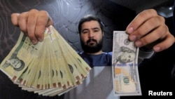 A money changer with a U.S dollar and the amount being given when converting it into Iranian rials at a currency exchange shop in Tehran's business district, January 20, 2016. 