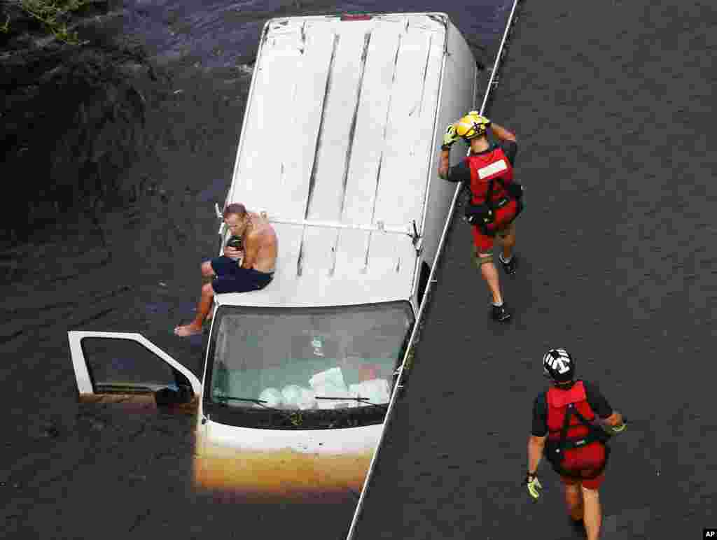 U.S. Coast Guard rescue swimmer Samuel Knoeppel, center, and Randy Haba, bottom right, approach to Willie Schubert on a stranded van in Pollocksville, North Carolina, in the aftermath of Hurricane Florence.