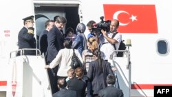 Thủ tướng Thổ Nhĩ Kỳ Ahmet Davutoglu (trái) vào máy bay với các con tin ngày 20/9/2014, tại sân bay ở thành phố Sanliurfa, miền nam Thổ Nhĩ Kỳ, gần biên giới Syria.
