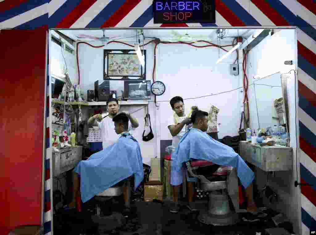 Filipino men get a haircut inside a barber shop near the Balintawak public market in metropolitan Manila, Philippines.