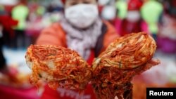 A woman poses for photographs with traditional side dish 'Kimchi' during the Seoul Kimchi Festival in central Seoul, South Korea, Nov. 4, 2016.