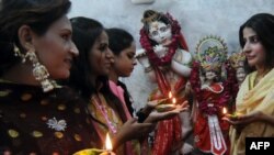 FILE - Pakistani Hindu women hold earthen oil lamps on the occasion of Diwali, in Lahore, on October 26, 2011. During Diwali, people honor Lakshmi, the Hindu goddess of wealth. 