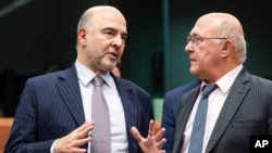 France's Finance Minister Michel Sapin, right, talks with European Commissioner for Economic and Financial Affairs Pierre Moscovici during an Eurogroup finance ministers meeting at the EU Council building in Brussels, Dec. 7, 2015. 