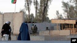 Civilians wait as Afghan security forces guard at the main gate of Kandahar civilian airport during a clash between Taliban fighters and Afghan forces, in Kandahar, Afghanistan, Dec. 9, 2015. 