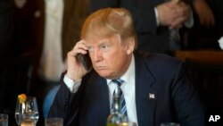 Le président Trump écoute son téléphone portable le 18 février 2016.