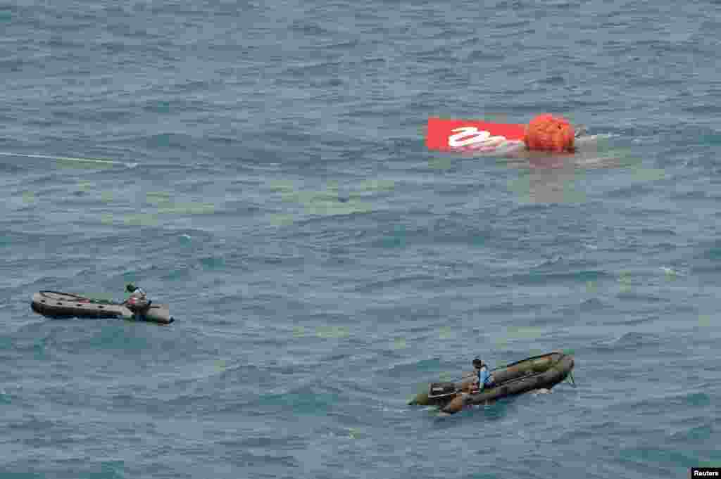 Part of the tail of AirAsia QZ8501 floats on the surface after being lifted as Indonesian navy divers conduct search operations for the black box flight recorders and passengers and crew of the aircraft, in the Java Sea, Jan. 10, 2015.