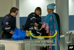 FILE - Custom officers check the luggage of a passenger at Charles de Gaulle airport, in Roissy, north of Paris, March 23, 2016.