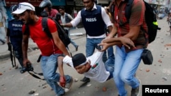 Pripadnici medija evakuišu aktivistu grupe Hifazat-i-Islam povređenog u sukobima sa policijom u Daki
