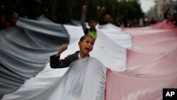 FILE - A boy chants slogans through a gap in a national flag raised by Shi'ite rebels, known as Houthis, during a protest against Saudi-led airstrikes in Sanaa, Yemen, April 15, 2016. 