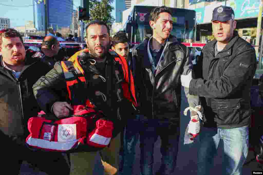 An Israeli medic and a police officer escort a wounded man at the scene of a stabbing in Tel Aviv, Jan. 21, 2015.