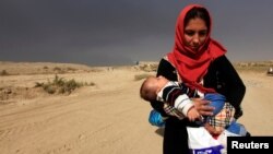 19일 이라크 군의 모술 탈환작전이 계속된 가운데, 주변 카이야라 마을의 한 여성이 아기를 안고 피난길에 올랐다.