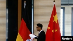 资料照片：2016年11月1日，在北京举行中德经贸部长会议期间一名男子走过中国和德国国旗。（路透社照片）