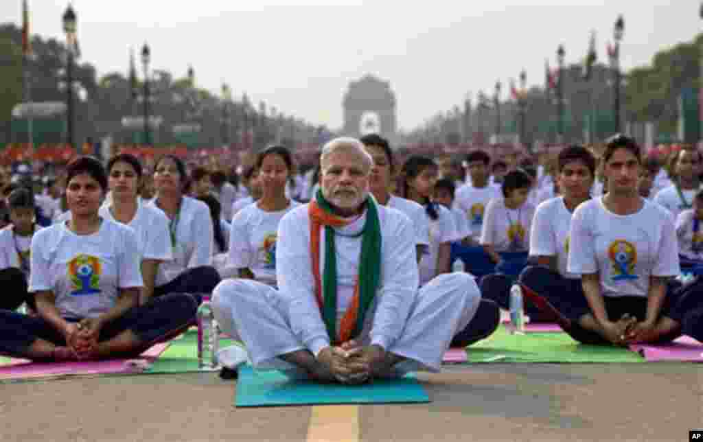Indian Prime Minister Narendra Modi, center, sits on a mat as he performs yoga along with thousands of Indians on Rajpath, in New Delhi, India, Sunday, June 21, 2015. Millions of yoga enthusiasts are bending their bodies in complex postures across India