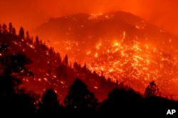 FILE - Seen in a long exposure photograph, embers light up hillsides as the Dixie Fire burns near Milford in Lassen County, Calif., on Tuesday, Aug. 17, 2021.