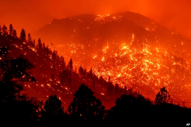 FILE - Seen in a long exposure photograph, embers light up hillsides as the Dixie Fire burns near Milford in Lassen County, Calif., on Tuesday, Aug. 17, 2021.