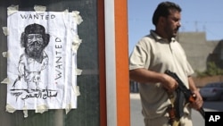 A rebel fighter stands next to an image representing Moammar Gadhafi at a checkpoint in Tripoli, Libya, August 30, 2011