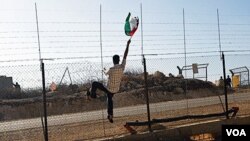 Seorang pria mengangkat bendera Palestina di depan para tentara Israel di Tepi Barat (foto dokumentasi).