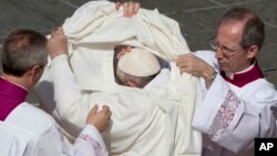 Le pape François aidé à se changer lors d'une cérémonie de canonisation à la place St Pierre, Vatican, 18 octobre 2015. (AP Photo/Alessandra Tarantino)