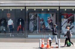 Pedestrians wearing face masks to protect against the coronavirus walk past the closed Adidas sportswear store, Thursday, May 7, 2020, in the Soho neighborhood of Manhattan. Nearly 3.2 million laid-off workers applied for unemployment benefits last week as the business shutdowns caused by the coronavirus outbreak deepened the worst U.S. economic catastrophe in decades. (AP Photo/Mary Altaffer)