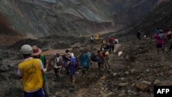 Rescuers recover bodies near the landslide area in the jade mining site in Hpakant in Kachin state on July 2, 2020. - The battered bodies of more than 120 jade miners were pulled from a sea of mud after a landslide in northern Myanmar on July 2 after one 